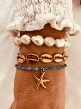 Load image into Gallery viewer, Gold shell bracelet layered with other jewelry showing trendy stacking style