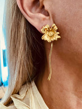 Load image into Gallery viewer, Gold flower earrings worn on the ear.
