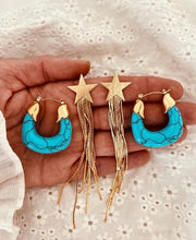 Učitaj sliku u preglednik galerije, Gold star drop earrings displayed on neutral background showcasing sleek modern jewelry design