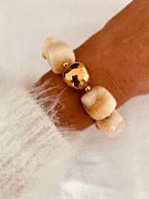 Load image into Gallery viewer, Cream Marble IZZA bracelet worn on the wrist, highlighting oversized glossy resin beads and elegant gold details.