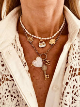Load image into Gallery viewer, MIA personalized necklace worn layered with a pearl necklace featuring a carved heart, vintage key, initial charm and symbolic gold pendants.