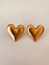 Load image into Gallery viewer, Gold heart earrings worn on the ear.