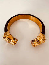 Load image into Gallery viewer, NYCOLE panther cuff bracelet photographed in hand, featuring genuine black leather and sculpted gold panther heads that create a luxurious statement jewelry piece.