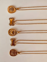 Load image into Gallery viewer, Gold necklace with a sparkling bone pendant styled on the hand, ideal for layering with other delicate gold necklaces.
