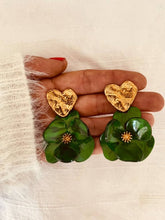 Load image into Gallery viewer, Pair of YNES green flower earrings displayed flat, showcasing the detailed resin petals, textured gold heart and polished stainless steel post.