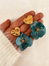 Load image into Gallery viewer, Pair of YNES turquoise flower statement earrings photographed on a white background, emphasizing the vibrant resin flower and luxurious gold heart detail.