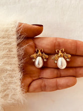 Učitaj sliku u preglednik galerije, Bee stud earrings with pearl and zircon details in gold stainless steel shown from front angle highlighting cute elegant jewelry design
