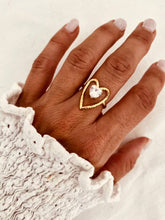 Load image into Gallery viewer, Gold plated stainless steel heart ring featuring a sparkling crystal centre on a woman's hand
