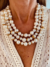 Load image into Gallery viewer, EMMELINA layered statement necklace worn around the neck featuring multiple strands of luminous artificial pearls with elegant gold accent beads.

