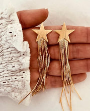 Učitaj sliku u preglednik galerije, Gold star tassel earrings with long metal drops shown from front angle highlighting glamorous statement jewelry design
