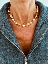 Učitaj sliku u preglednik galerije, LEAKENA freshwater pearl statement necklace worn around the neck featuring genuine freshwater pearls paired with sculptural textured gold elements for a timeless elegant look.
