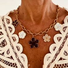 Učitaj sliku u preglednik galerije, HADDIE flower charm necklace worn around the neck featuring a bold gold chain with elegant black, ivory and beige enamel flower pendants for a luxurious statement look.
