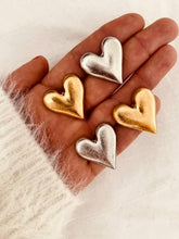 Load image into Gallery viewer, Collection of oversized heart statement earrings available in gold and silver finishes with a modern brushed metallic texture.
