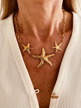 Load image into Gallery viewer, LUNA gold statement necklace featuring three sculptural starfish.

