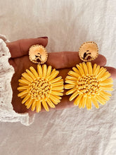 Load image into Gallery viewer, NAYA yellow flower statement earrings worn on the ear, showcasing the handwoven raffia flower and polished gold stud for a vibrant summer look.
