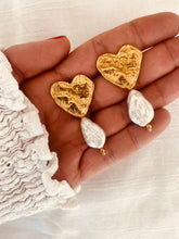 Učitaj sliku u preglednik galerije, Close-up of the NIKA heart earrings highlighting the textured gold finish and luminous baroque pearls.
