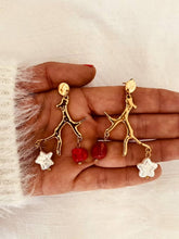 Load image into Gallery viewer, Gold tree branch statement earrings displayed in the hand featuring a natural freshwater pearl and vibrant red stone suspended from an organic branch design.
