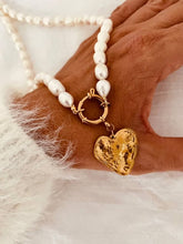 Učitaj sliku u preglednik galerije, Nancy freshwater pearl necklace with a textured gold heart pendant displayed in a hand, highlighting genuine pearls and elegant front clasp.
