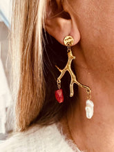 Load image into Gallery viewer, NIRA earrings worn on the ear showcasing elegant gold tree branches decorated with a freshwater pearl and red stone charms.
