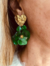 Load image into Gallery viewer, YNES green flower statement earrings worn on the ear, featuring a textured gold heart stud and a large handcrafted green resin flower with detailed petals.

