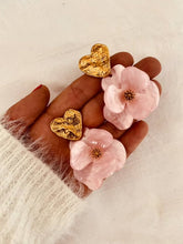 Load image into Gallery viewer, Pair of YNES soft pink flower earrings displayed flat, featuring handcrafted resin petals suspended from a textured gold heart stud.
