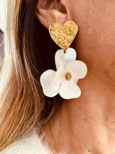 Load image into Gallery viewer, YNES white flower statement earrings on the ear featuring a sculptural white resin flower and textured gold heart with a lightweight comfortable design.
