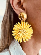 Load image into Gallery viewer, Pair of NAYA yellow raffia flower earrings photographed in a hand, highlighting the handcrafted floral design and lightweight statement style.
