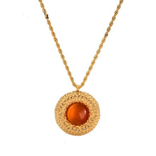 Load image into Gallery viewer, Medallion pendant necklace featuring red center stone surrounded by intricate gold detailing creating a bold and luxurious design
