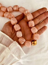 Load image into Gallery viewer, Hand wearing a pink beaded bracelet with a gold accent on a white background
