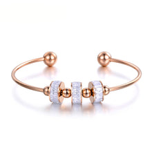Load image into Gallery viewer, Rose gold stainless steel bangle bracelet with black and white roller details displayed in clean product view
